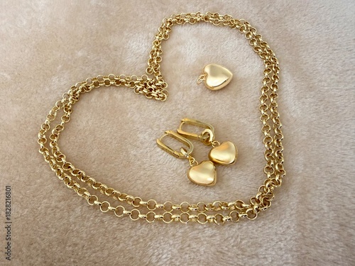 A gold-plated silver jewelry set featuring a delicate chain with a heart pendant and matching heart drop earrings. Elegant accessories for fashion, gifts, and romantic themes