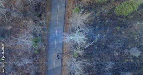 Drone tracking rider, teen riding bike on yellow centerline, grid flare tracing route for leisure