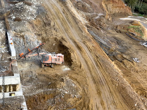 View of an earthmover on a construction site, leaving tracks on the bare ground, against a backdrop of raw soil and concrete structures, Istanbul, Istanbul, Turkey.