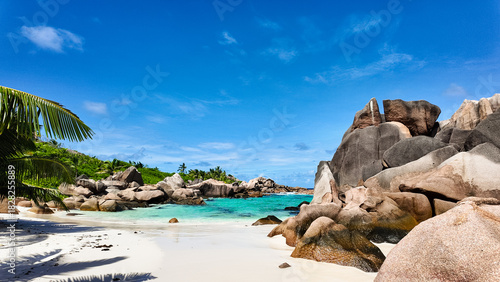 Secluded bay with turquoise water, white sandy beach, and granite boulders under a blue sky. Seychelles, La Digue. Anse Cocos.