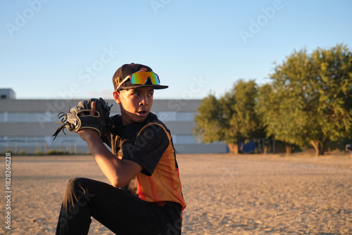 Young baseball pitcher in uniform with glove ready to throw during a game