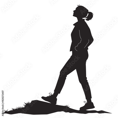 Silhouette of a young woman walking confidently on uneven terrain with her hands in her pockets and looking upwards towards the sky