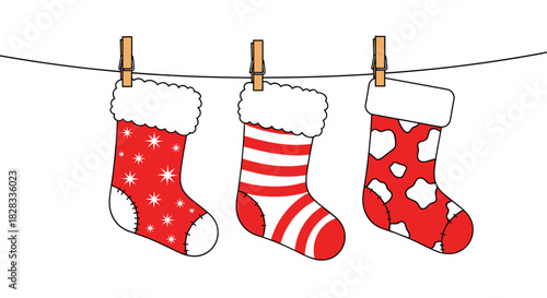 Three festive red and white Christmas stockings with different patterns hanging from a clothesline with wooden pins for the holidays.