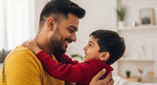 A father in a yellow shirt hugs his young son in a red sweater, sharing an affectionate and heartfelt moment