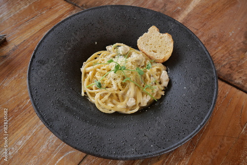 Carbonara, a classic Italian pasta dish topped with a creamy and savory cheese sauce, is served on the table.