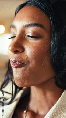 Bite, chocolate and satisfaction with Indian woman in home living room for craving or indulgence. Candy, eating and snack with happy person in apartment for delicious junk food, bokeh or sweet treat