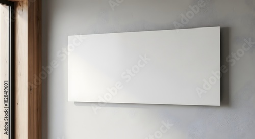 Modern white infrared wall heater panel mounted on a textured gray wall next to a wooden window frame in a contemporary interior space