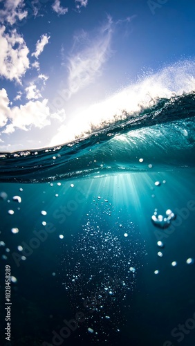 Split-level view of ocean with sunlight streaming through the water's surface