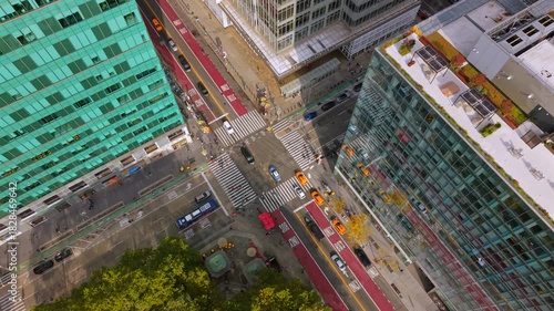 Cinematic aerial view of Manhattan New York City, New York showing angled intersection scene with glass buildings, red bus lanes, traffic, taxis and crosswalks creating a vivid detailed urban layout