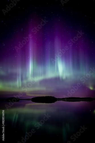 Amazing aurora borealis dancing over lake in Farnebofjarden national park in north of Sweden