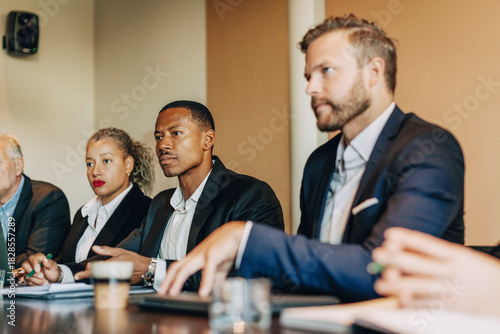 Concentrated male business entrepreneur sitting with colleagues in meeting at law firm