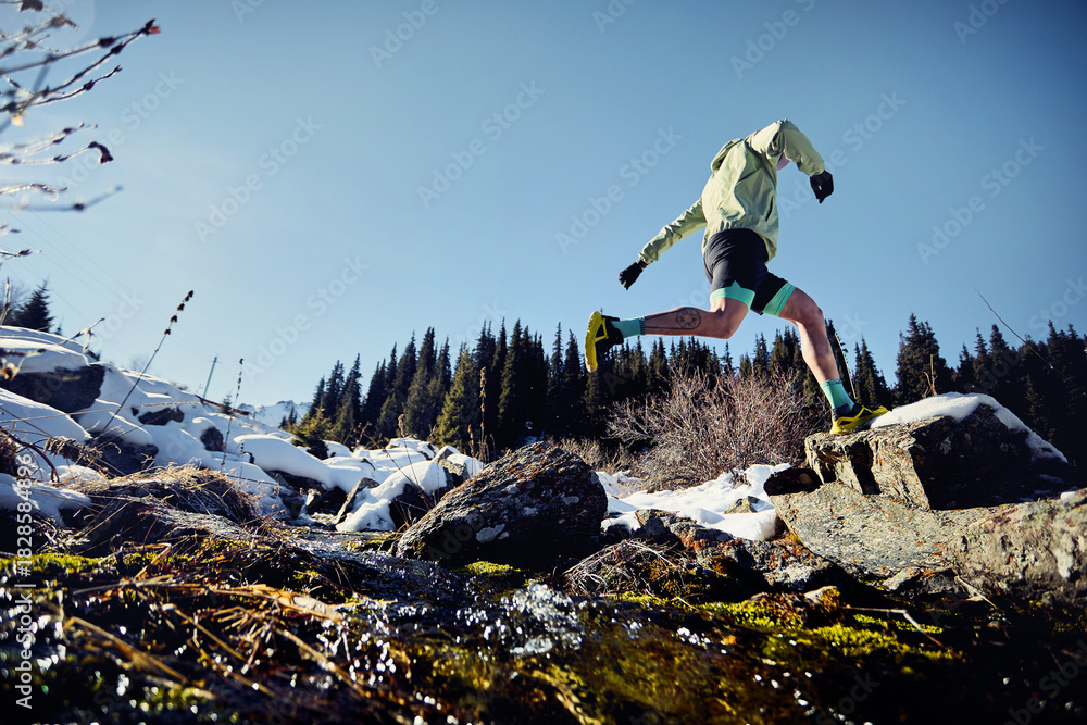 Obraz premium Man running trough the river in the winter mountains