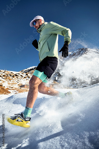 Man running at snow trail in the winter mountains
