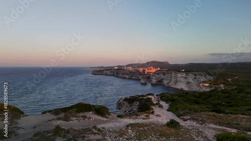 Cinematic Aerial Drone Approach Shot Over the Dramatic White Limestone Cliffs Towards the Historic Bonifacio Citadel City and Mediterranean Sea at Golden Hour, Corsica, France.