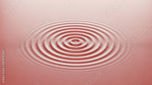 Circular ripples expanding outwards on a surface with a soft pink gradient background effect creating waves