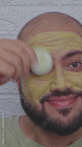 Vertical Video of Man Playing with Cucumber with Clay Mask on Face