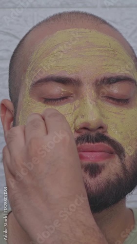 Vertical Video of Man Removing Clay Face Mask with Cotton Ball