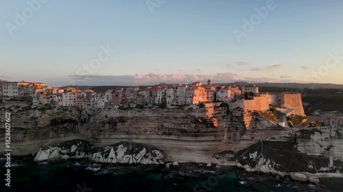 Expansive Aerial Drone Pan Across the Dramatic White Limestone Cliffs of Bonifacio, Revealing the Historic Citadel City and Turquoise Mediterranean Coastline at Sunrise, Corsica, France.