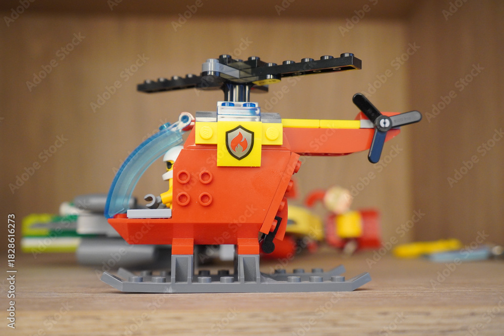 Naklejka premium A detailed shot of a Lego City fire helicopter toy on a wooden surface.