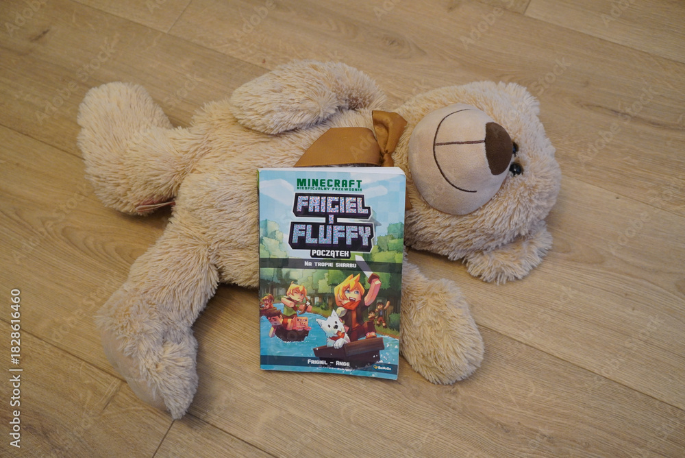 Naklejka premium A plush teddy bear with a Minecraft book on a wooden floor