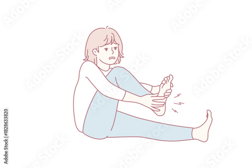woman massaging sore foot after run, sitting on floor with one leg extended and winced expression.