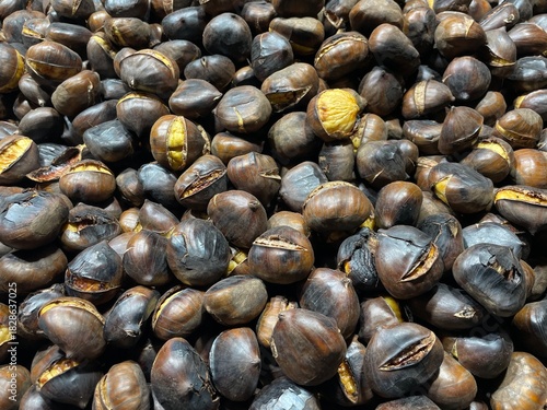 close-up photo of a pile of roasted chestnuts: large chestnuts, also known as marroni, cooked in a large pan after being harvested in November in northern Italy