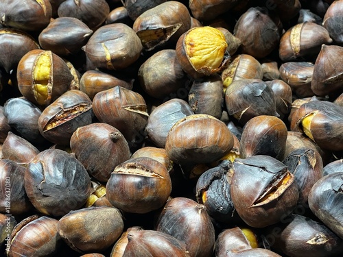 close-up photo of a pile of roasted chestnuts: large chestnuts, also known as marroni, cooked in a large pan after being harvested in November in northern Italy