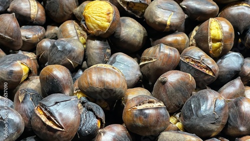 close-up photo of a pile of roasted chestnuts: large chestnuts, also known as marroni, cooked in a large pan after being harvested in November in northern Italy