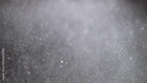 Raindrops falling on a dark surface, creating a mesmerizing and calming visual effect.