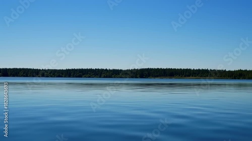 Serene Lake Landscape with Clear Blue Sky and Forest Horizon.