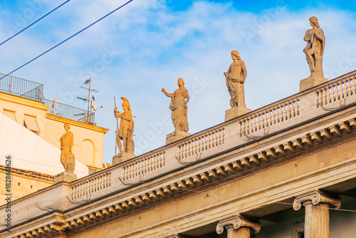 Classical statues on rooftop balustrade of historic building in Italy