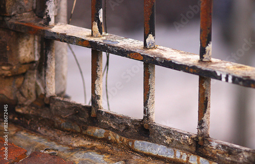 Close-up of old rusty bars in the window of an aged industrial building.