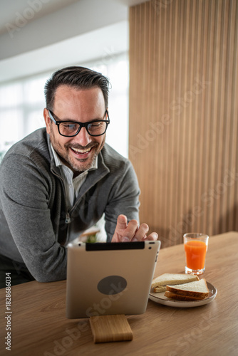 Man laughing during video call having breakfast at home