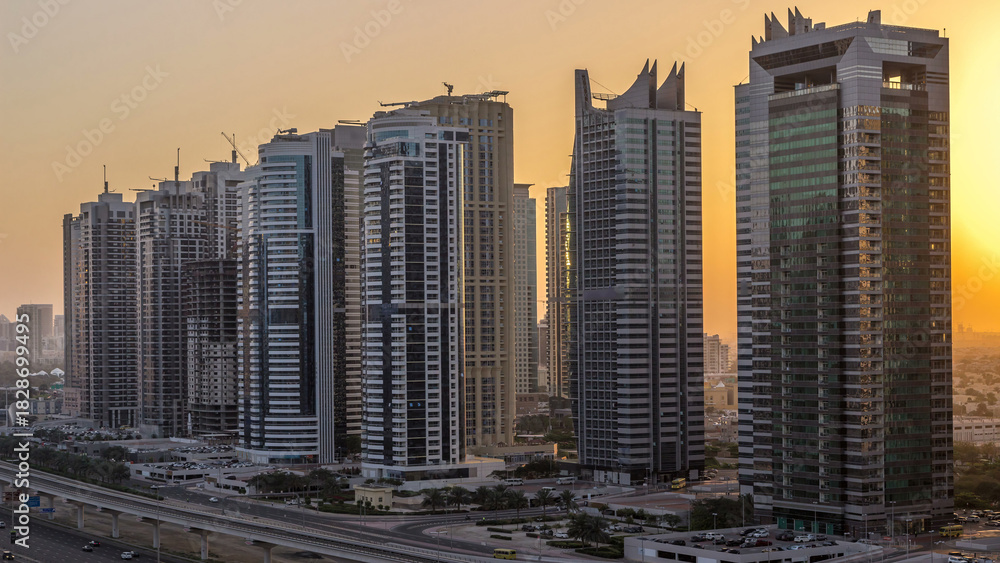 Fototapeta premium Aerial view of Jumeirah lakes towers skyscrapers night to day timelapse with traffic on sheikh zayed road.