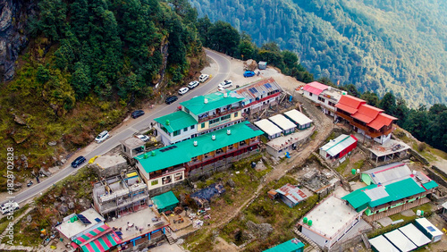 Aerial drone village town on cliff mountain edge with small concrete green red houses, narrow road and mountains in the distance in Chopta Tungnath uttarakhand India