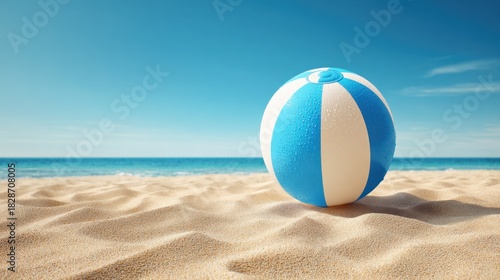 A vibrant beach ball rests on soft golden sand as gentle waves lap at the shore under a bright blue sky. The scene captures a peaceful moment by the sea.