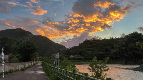 Spectacular sunrise with dramatic orange and golden clouds illuminating the dark silhouette of Wulai mountains in New Taipei City Taiwan at dawn.