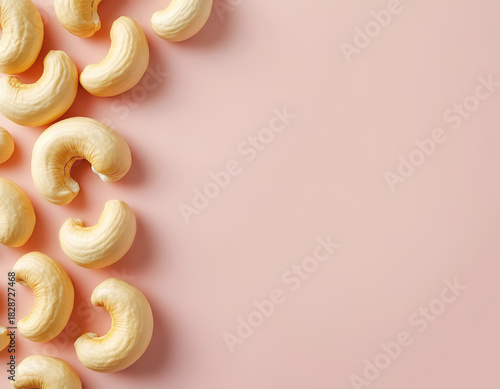 Cashew nuts and pieces laying on light pink background. Samle for design