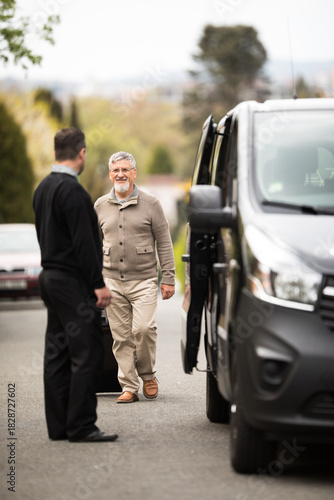 Senior man getting picked-up for his airport transfer by a private shuttle service driver. Commericial trasfer cargo transportation company fleet. Vip charter
