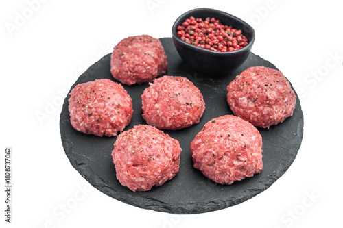 Fresh raw meatballs Frikadelwith pepper on black stone plate over light background ideal for cooking, protein and food preparation themes.