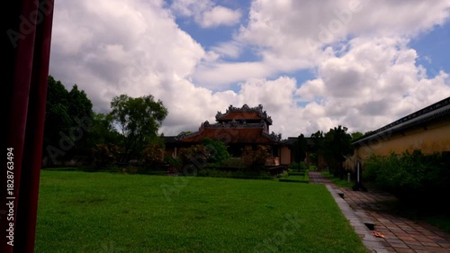A wooden frame reveals the two-story Minh Lau Pavilion, perched on a rustic stone base amidst manicured geometric gardens