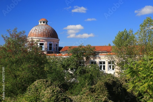 Abandoned dome building with overgrown vegetation and blue sky in background