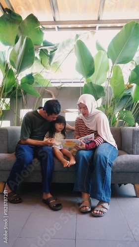 Loving Asian Family Reading Storybook Together on Sofa