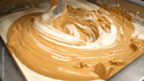 Creamy peanut butter being mixed in a large industrial churning machine for food production