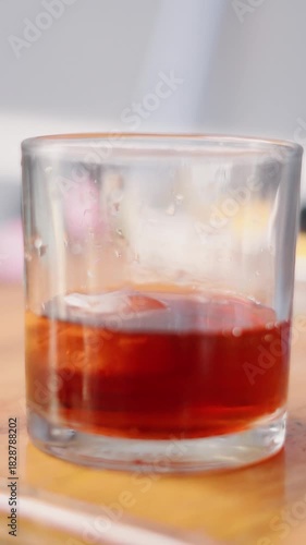 Hand Dropping Ice Cube into a Glass of Dark Beverage