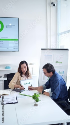 Asian business professionals collaborate discuss data charts office meeting analyzing strategy financial report workplace teamwork productivity