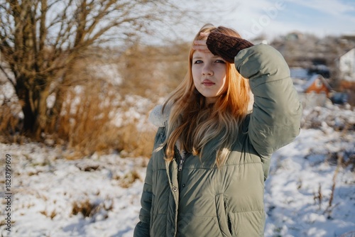 A stylish 12-year-old teenage girl walks through a picturesque winter field. Authentic moment of seasonal beauty, youthful elegance and natural winter exploration