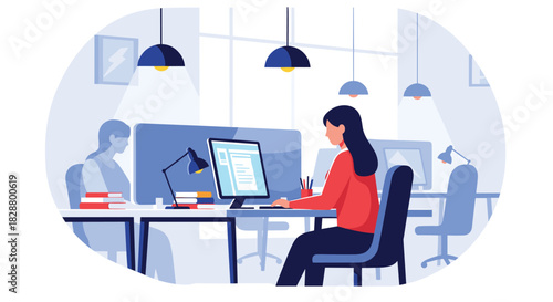 Young woman working on her computer at a desk in a modern open-plan office with other colleagues in the background.