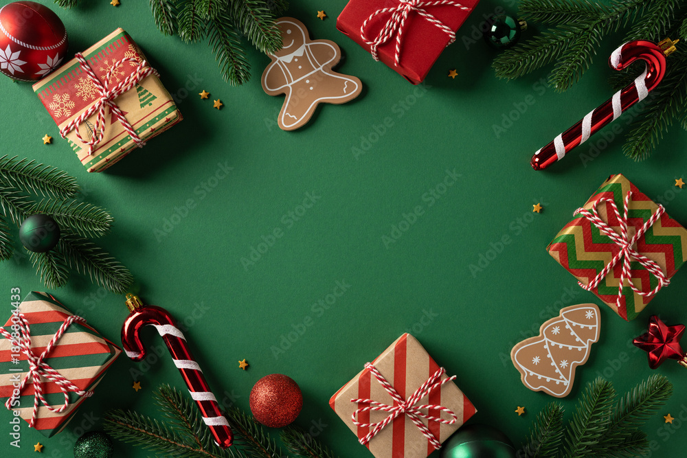 Obraz premium Vibrant Christmas scene featuring wrapped gifts, candy cane, gingerbread figures, pine needles, and holiday ornaments arranged around a green backdrop