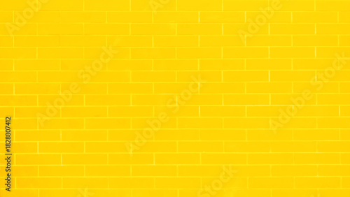 A brick wall with a yellow color. The wall is made of bricks and has a rough texture